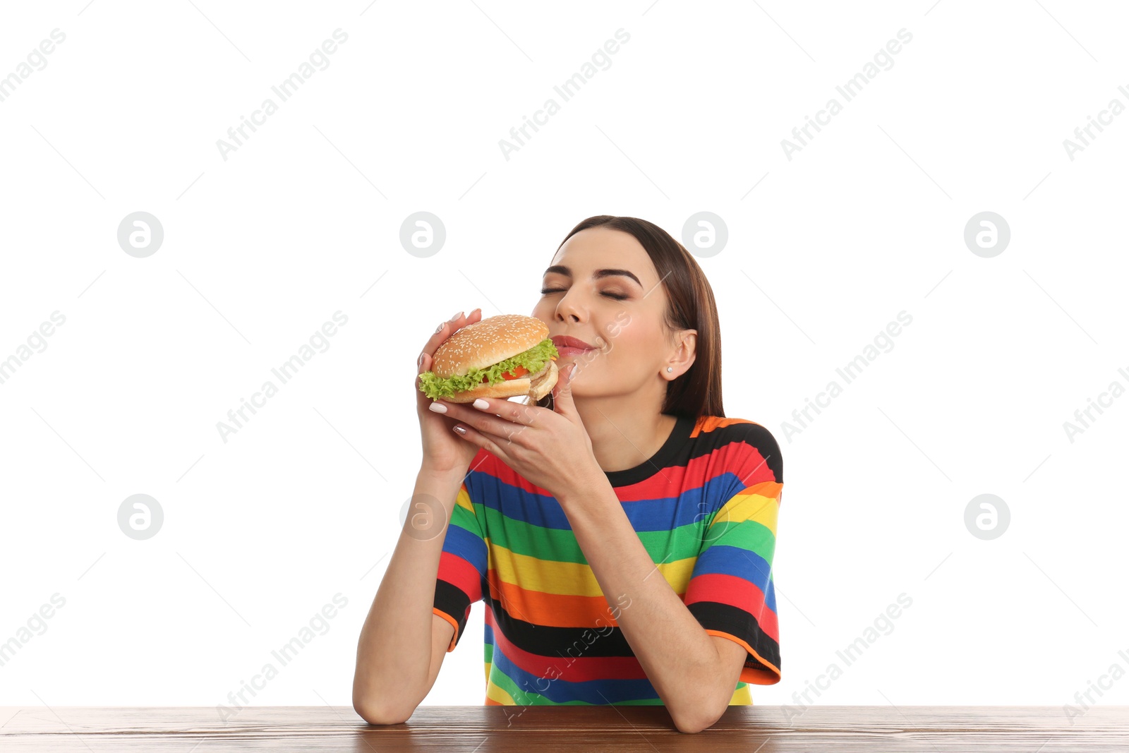 Photo of Young woman eating tasty burger at table on white background