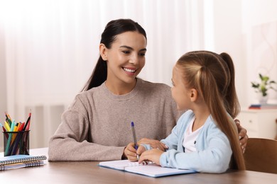 Dyslexia problem. Mother helping daughter with homework at table in room