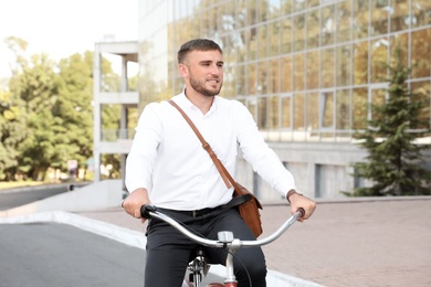 Photo of Attractive man riding bike on city street