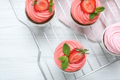 Photo of Delicious cupcakes with cream and strawberries on white wooden table, top view