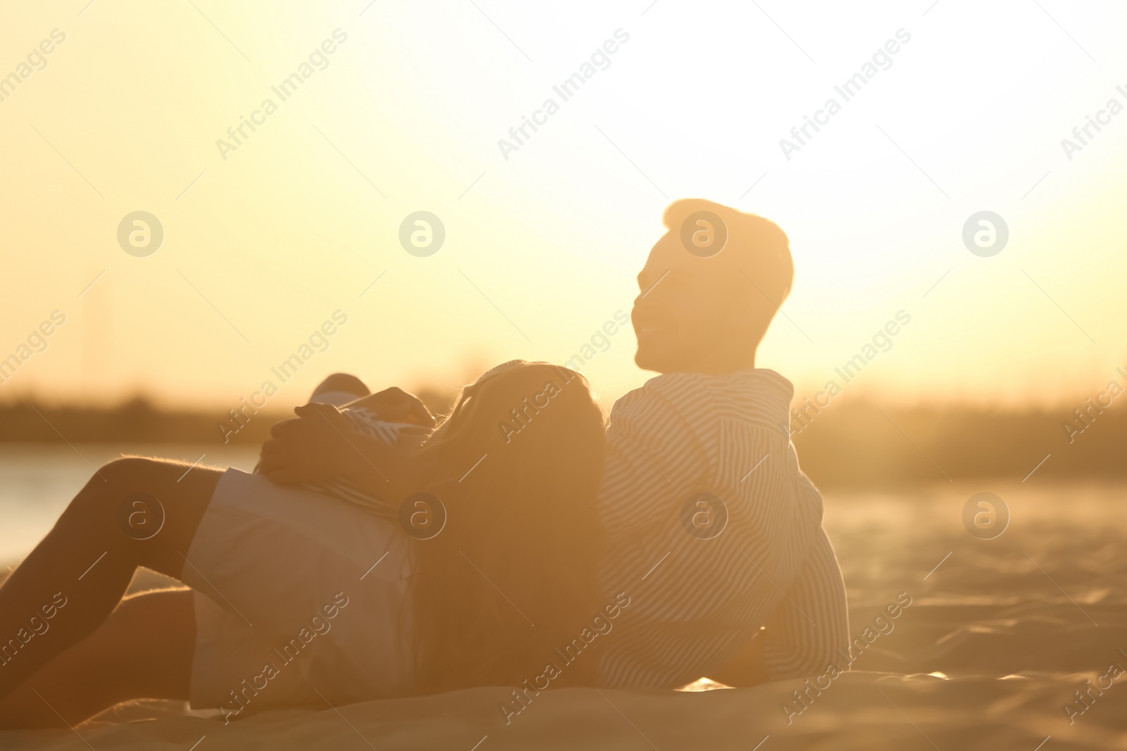 Photo of Happy young couple resting together on beach at sunset