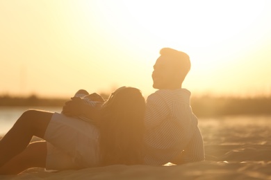 Photo of Happy young couple resting together on beach at sunset