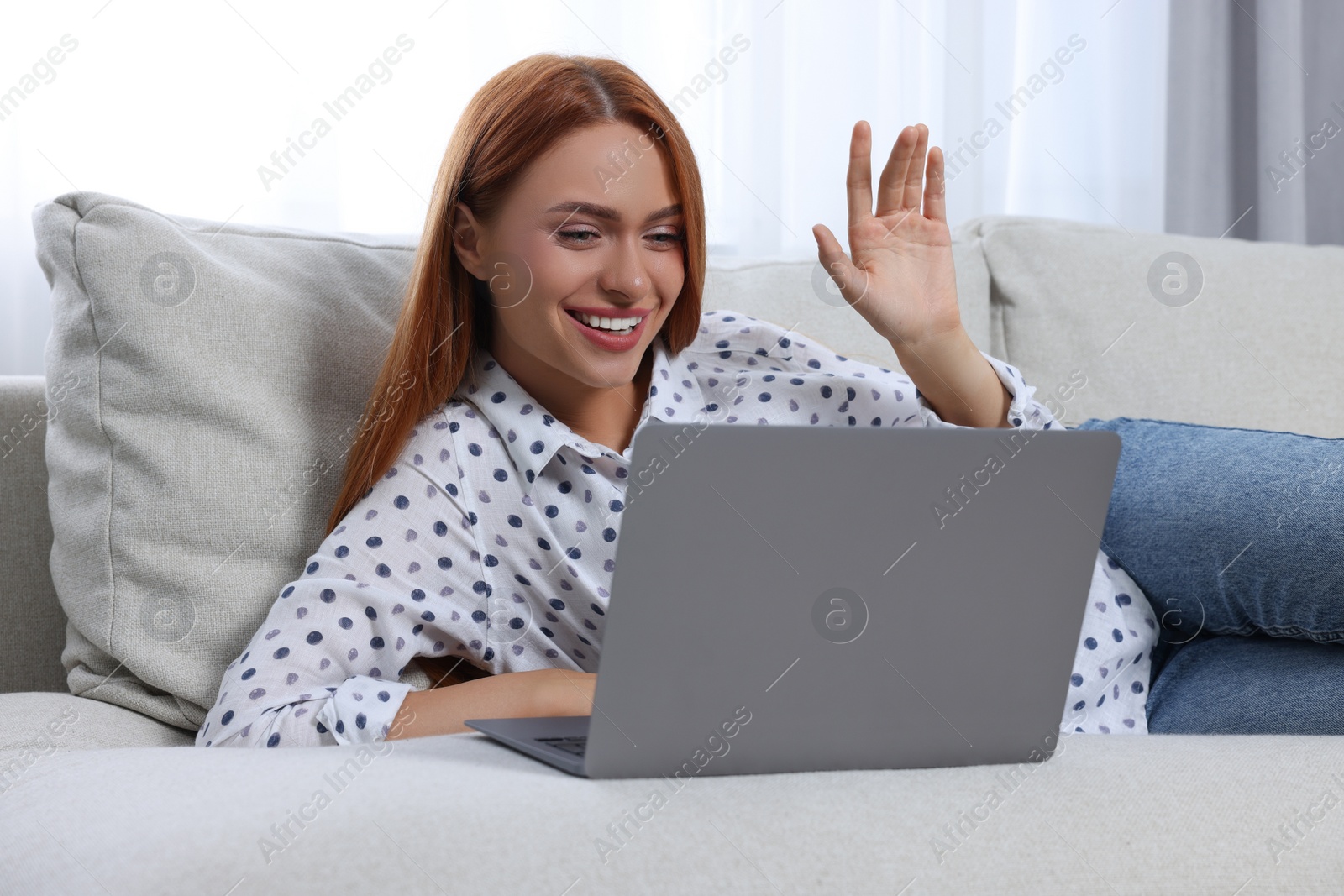 Photo of Woman waving hello during video chat via laptop at home