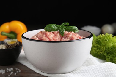Photo of Raw chicken minced meat with basil on wooden table, closeup