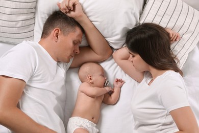 Couple and baby sleeping on bed together, top view