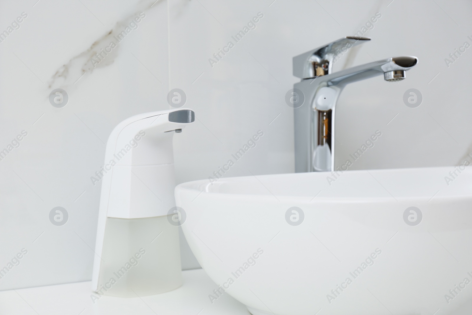 Photo of Modern automatic soap dispenser near sink in bathroom, closeup