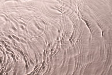 Photo of Rippled surface of clear water on beige background, top view