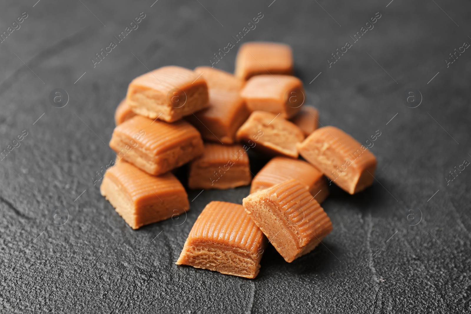 Photo of Delicious caramel candies on dark background