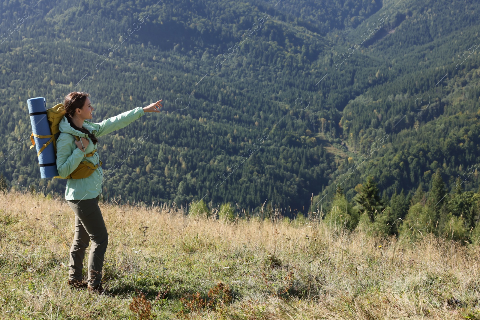 Photo of Tourist with backpack and sleeping pad in mountains on sunny day