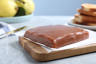 Wooden board with fresh quince paste on light grey table, closeup