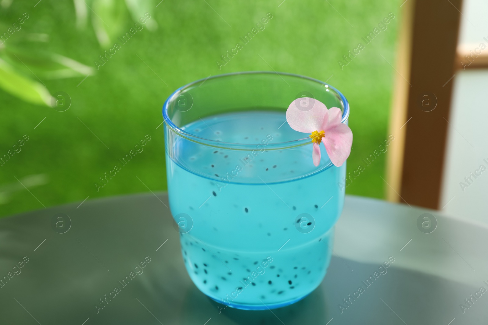 Photo of Tasty light blue drink with basil seeds on table