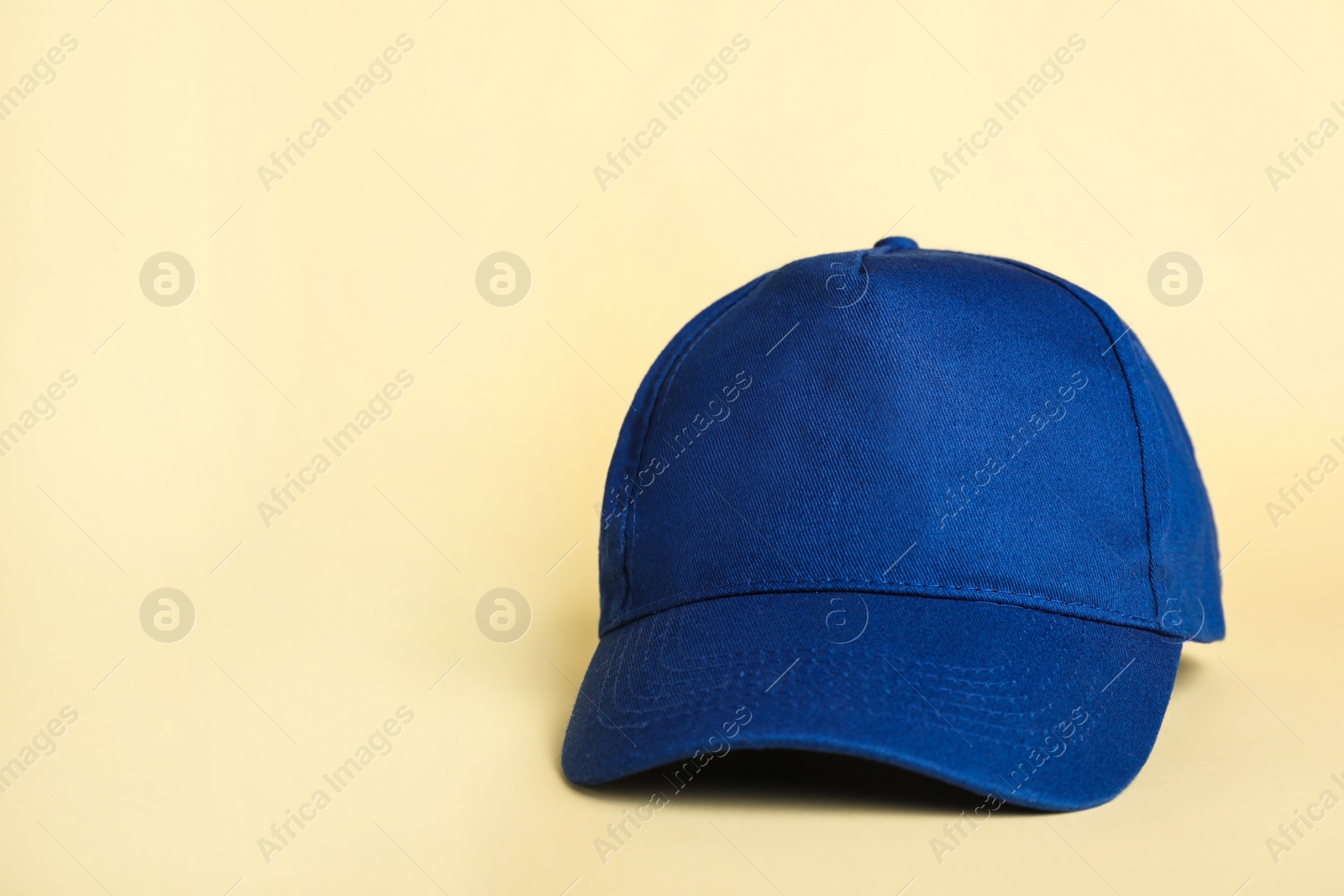 Photo of Stylish blue baseball cap on beige background. Space for text