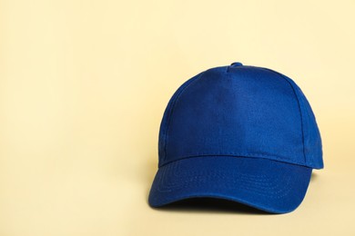 Photo of Stylish blue baseball cap on beige background. Space for text