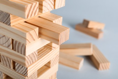 Photo of Jenga tower made of wooden blocks on grey background, closeup. Space for text