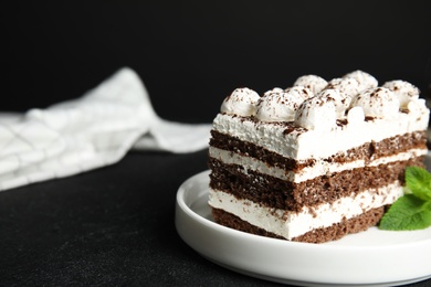 Tiramisu cake with mint on table against dark background, closeup. Space for text