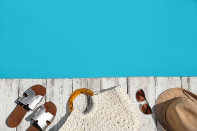 Beach accessories on wooden deck near outdoor swimming pool, flat lay. Space for text