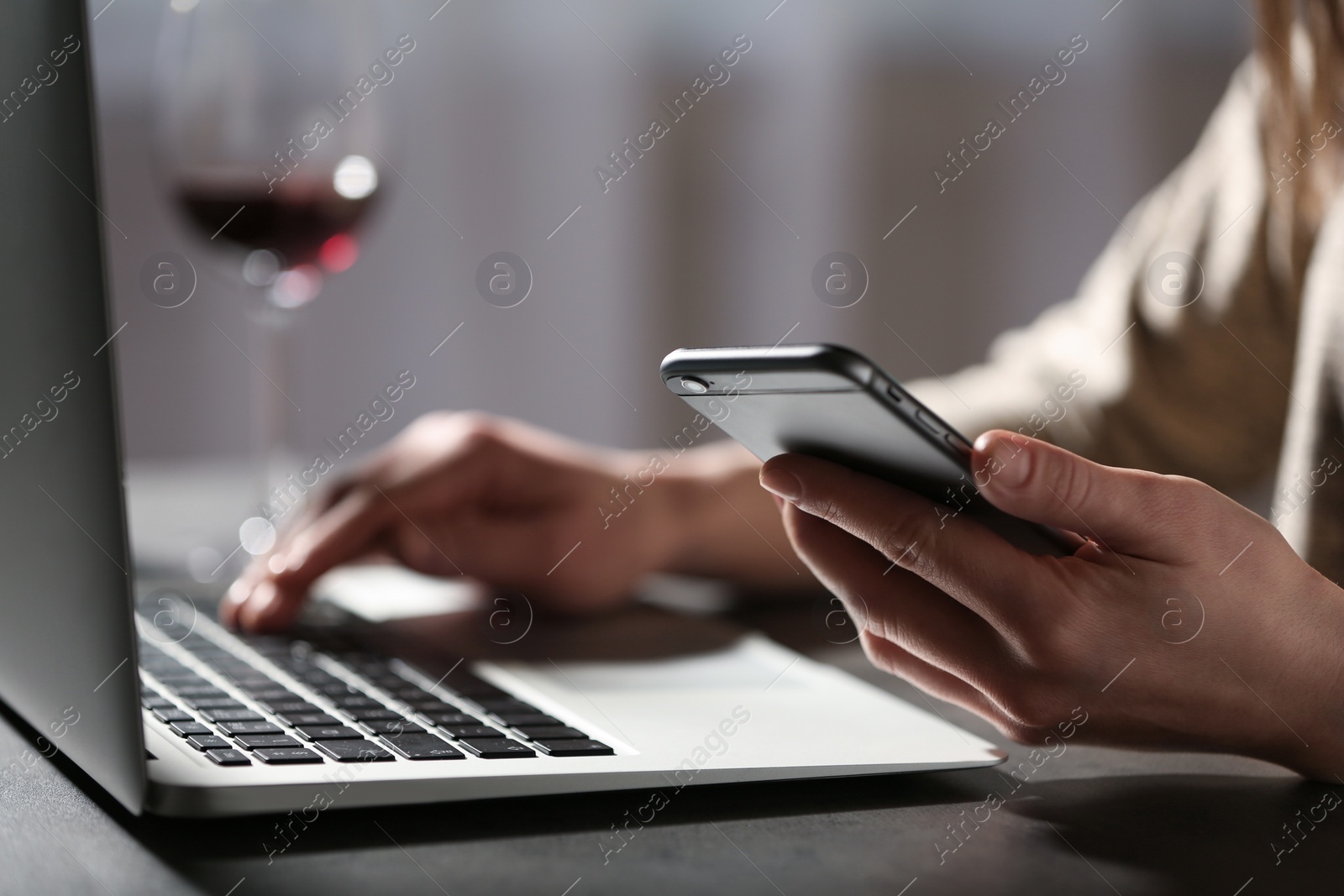 Photo of Woman using smartphone and laptop at table indoors, closeup. Loneliness concept