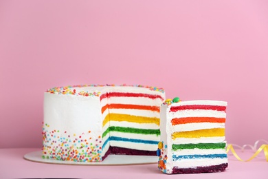 Photo of Delicious rainbow cake on color background