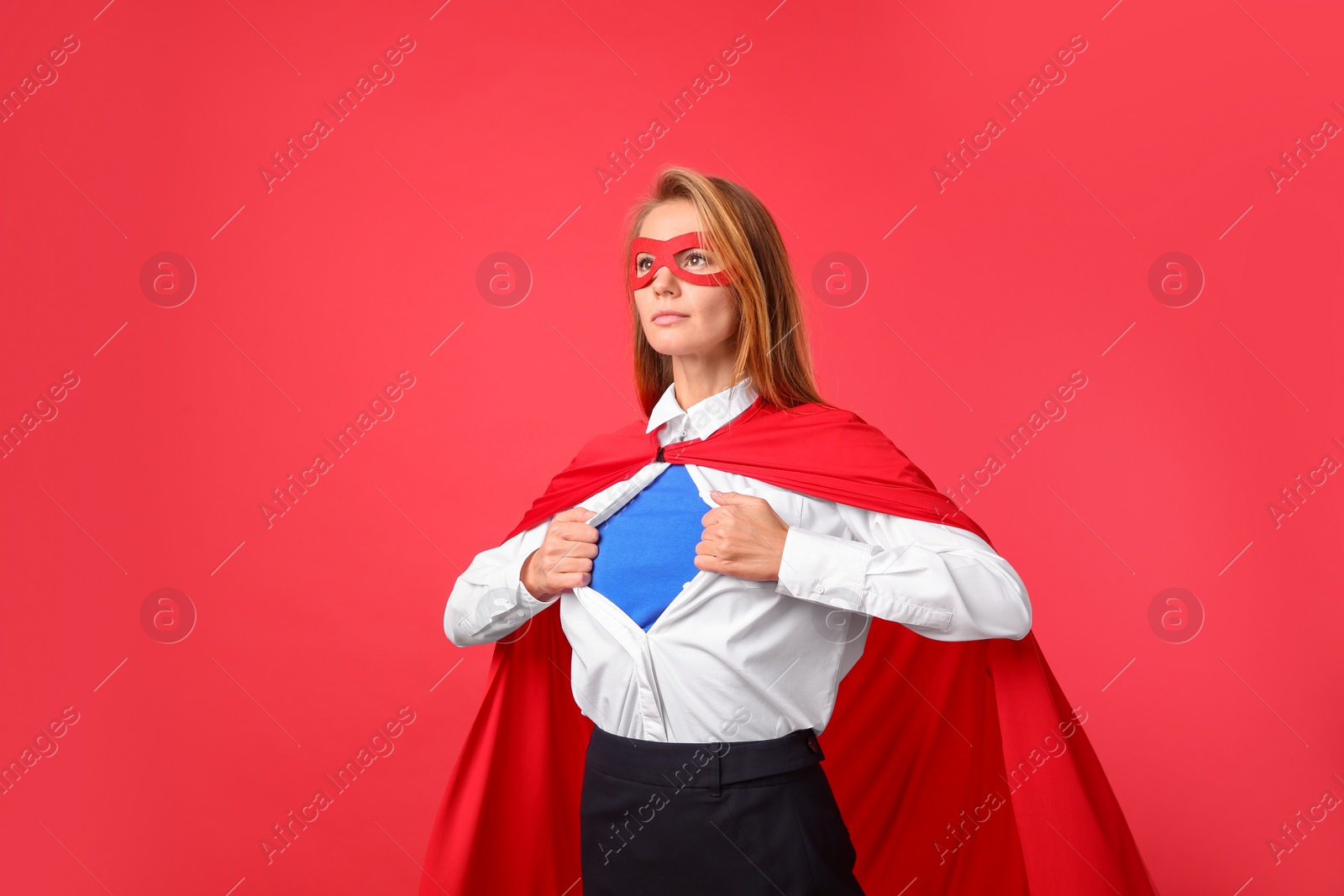 Photo of Confident businesswoman wearing superhero costume under suit on red background