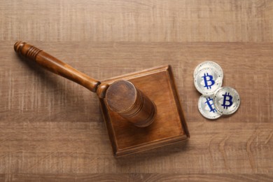 Photo of Law concept. Gavel and bitcoins on wooden table, top view