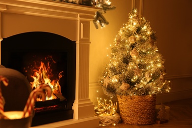 Photo of Beautiful Christmas tree near fireplace in room