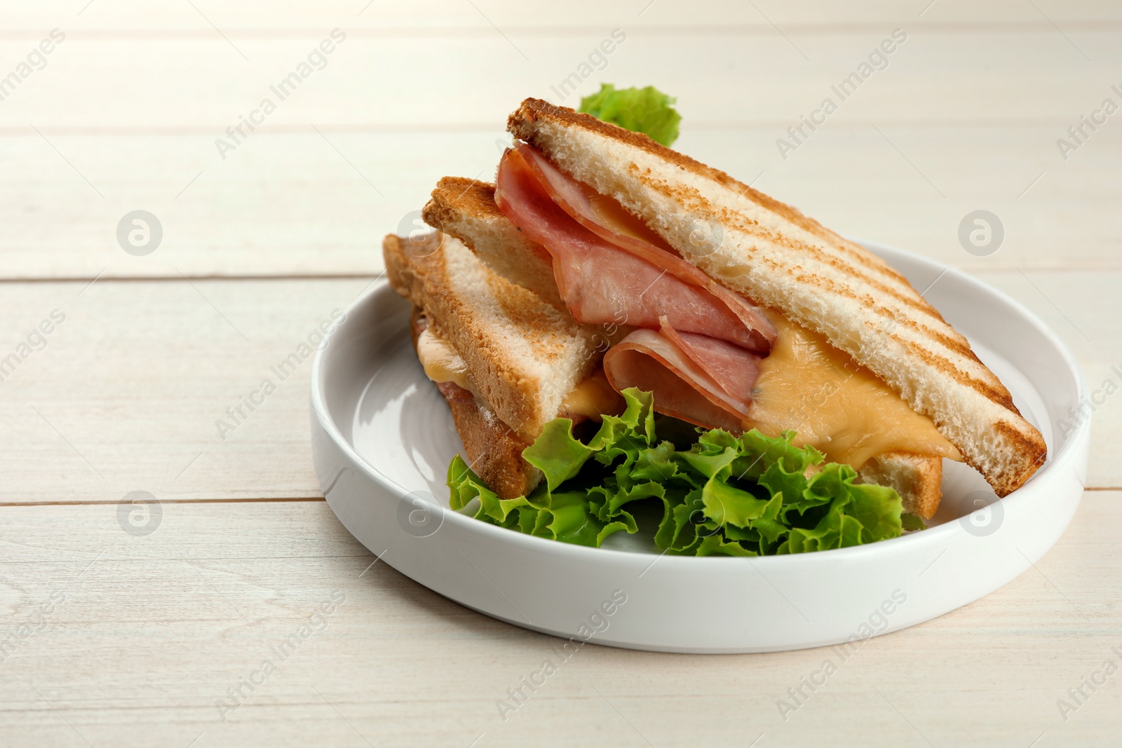 Photo of Tasty sandwiches with ham, lettuce and melted cheese on white wooden table, closeup. Space for text