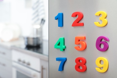 Photo of Colorful magnetic numbers on refrigerator door in kitchen. Space for text