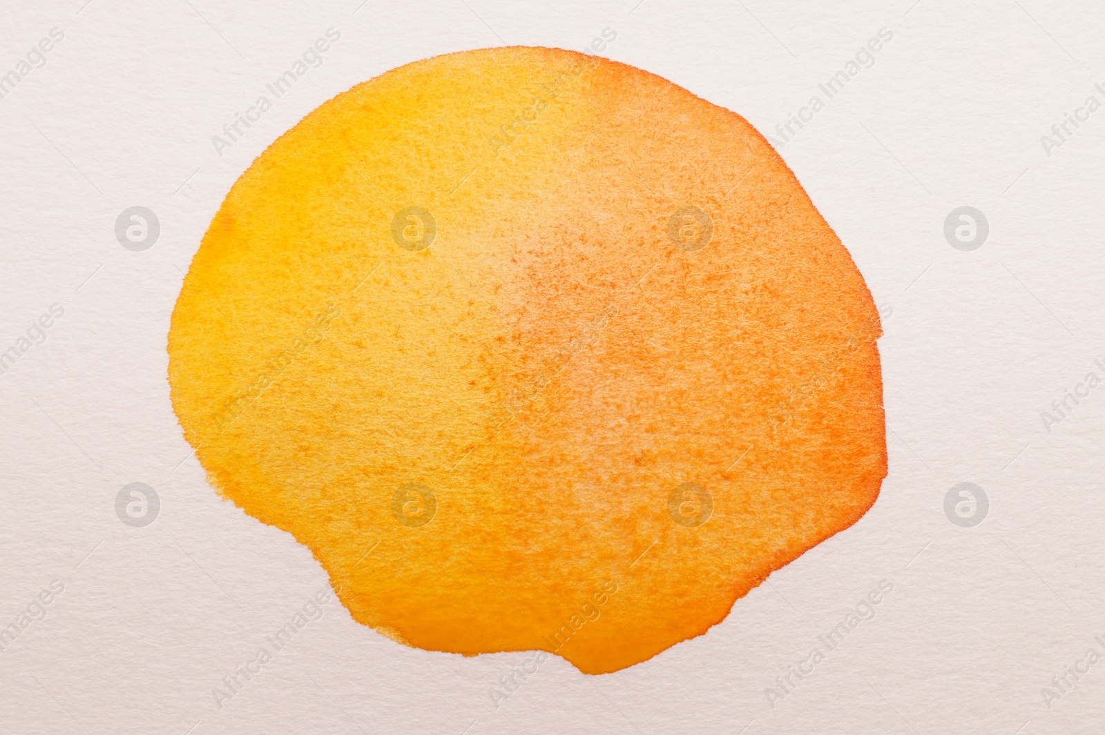 Photo of Blot of orange watercolor paint on white paper, top view