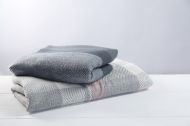 Photo of Stylish soft scarfs on white wooden table
