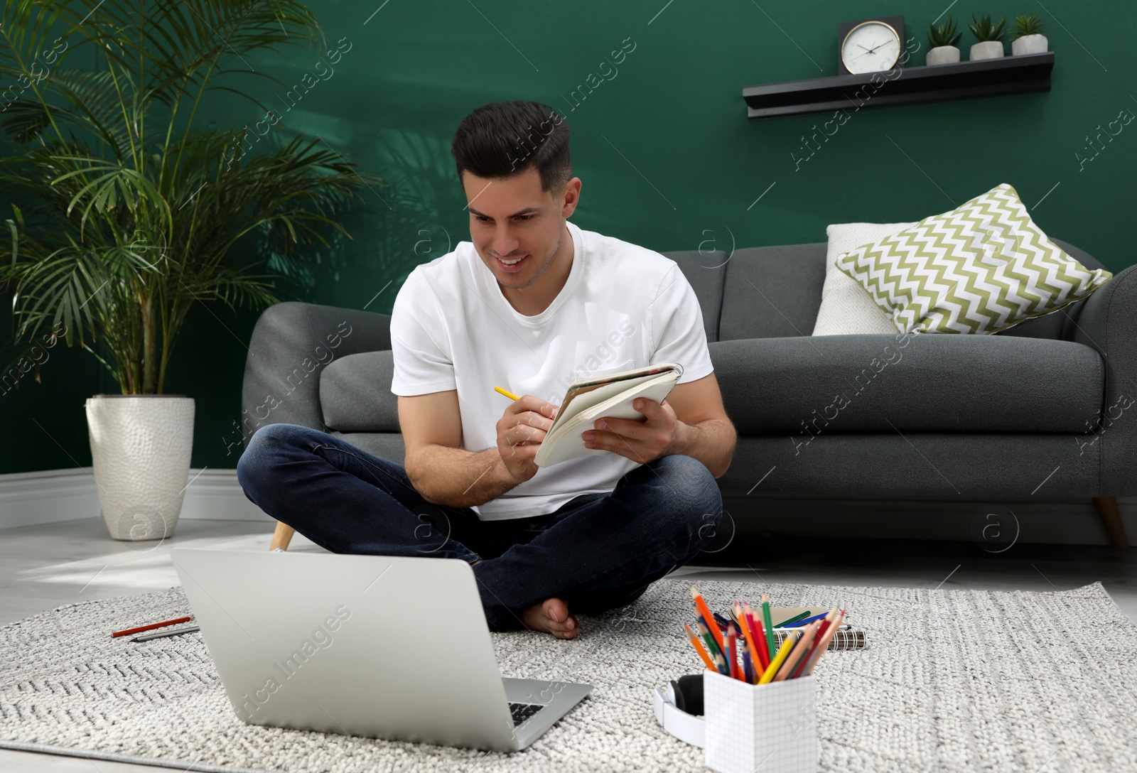 Photo of Man drawing in notebook at online lesson indoors. Distance learning