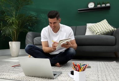 Man drawing in notebook at online lesson indoors. Distance learning