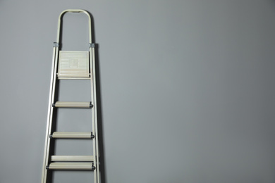 Photo of Metal stepladder on grey background. Space for text