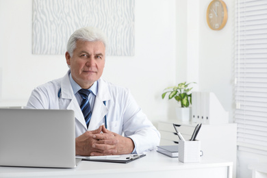 Portrait of senior doctor in white coat at workplace