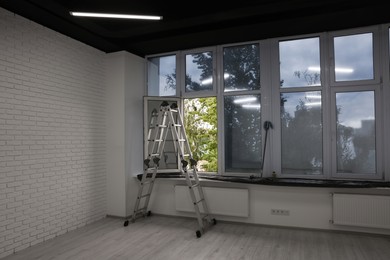 Photo of Ladder in empty renovated room with windows