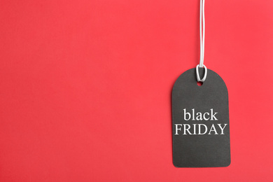 Photo of Tag with words BLACK FRIDAY on red background, top view. Space for text