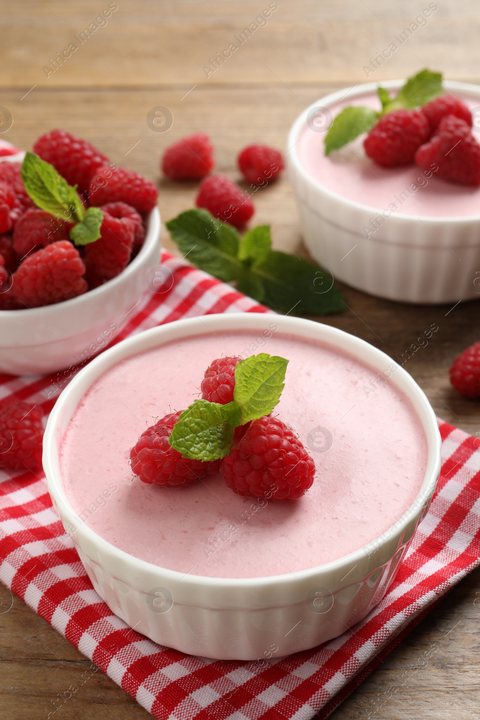 Photo of Delicious raspberry mousse with mint on wooden table