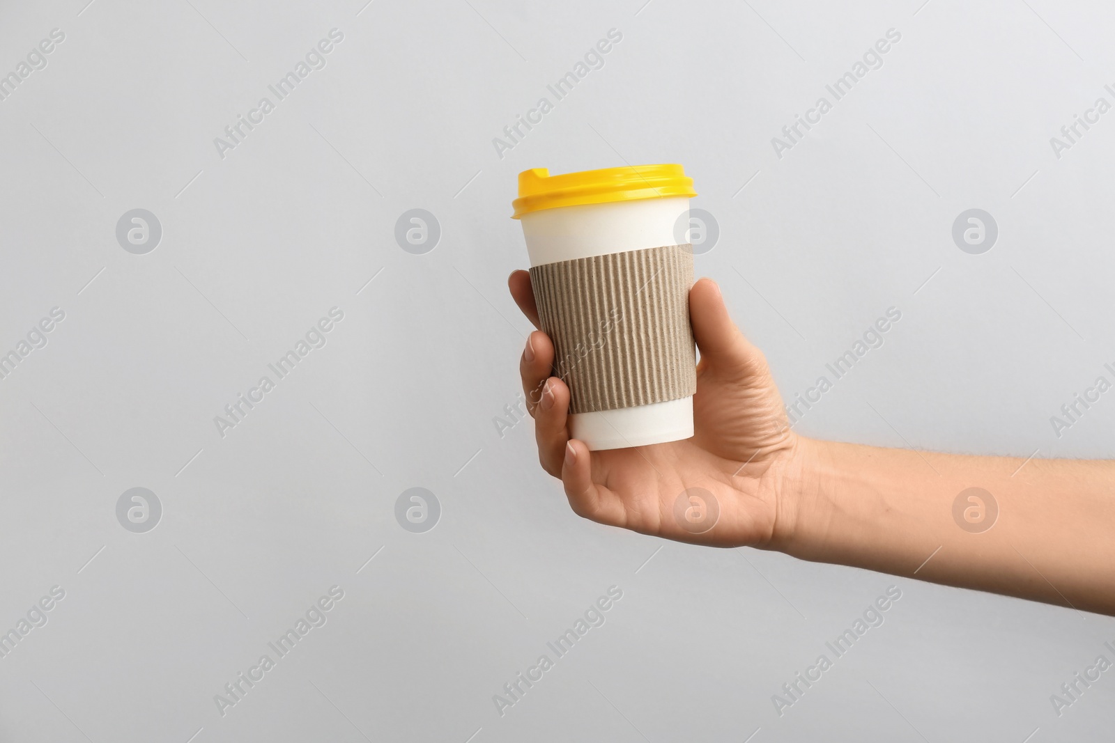 Photo of Woman holding takeaway paper coffee cup on light background