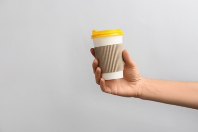 Photo of Woman holding takeaway paper coffee cup on light background