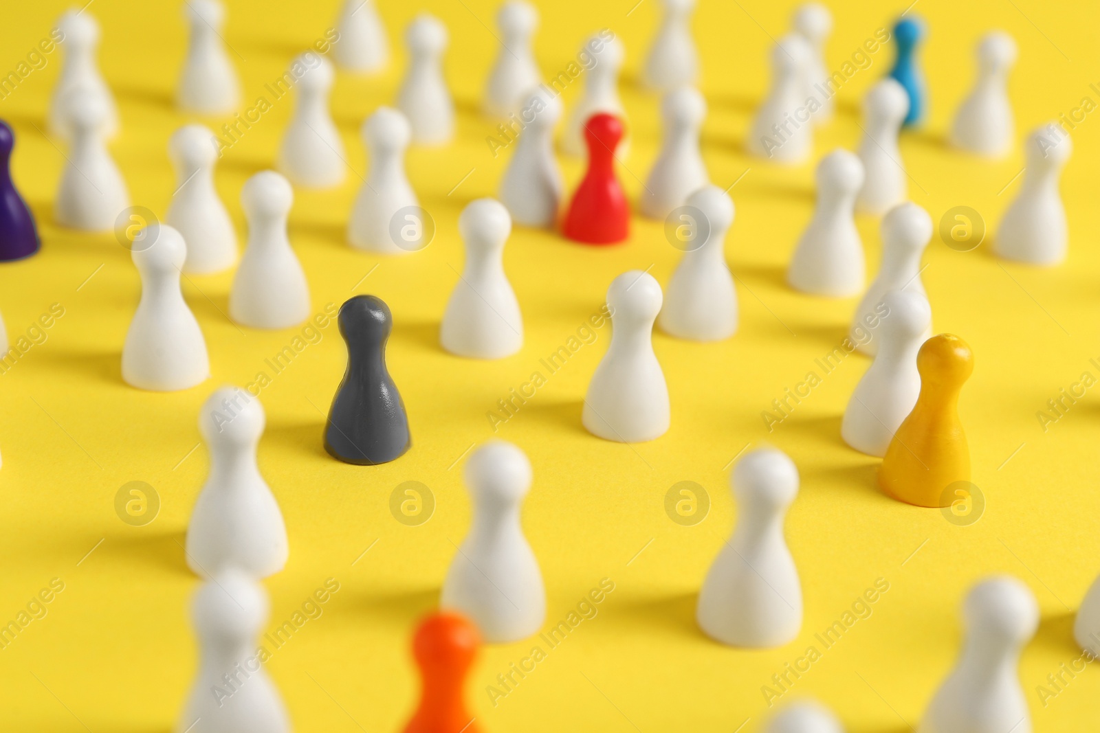 Photo of Colorful pawns on yellow background, closeup. Social inclusion concept