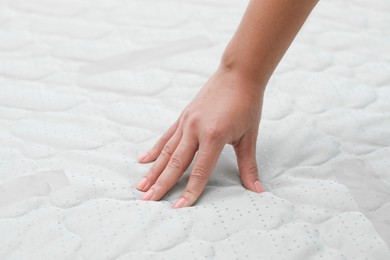 Photo of Woman touching new soft mattress, closeup view