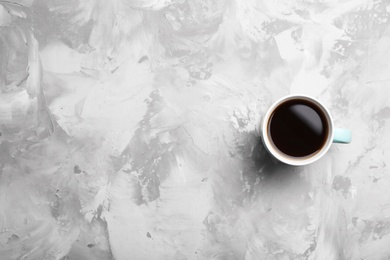 Ceramic cup with hot aromatic coffee on grunge background, top view