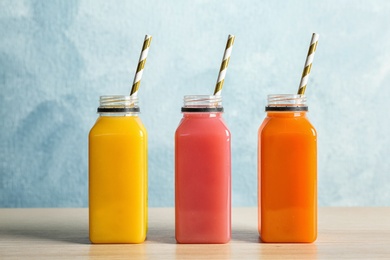 Photo of Bottles with tasty juices on table against color background