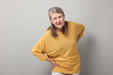 Photo of Arthritis symptoms. Woman suffering from back pain on gray background