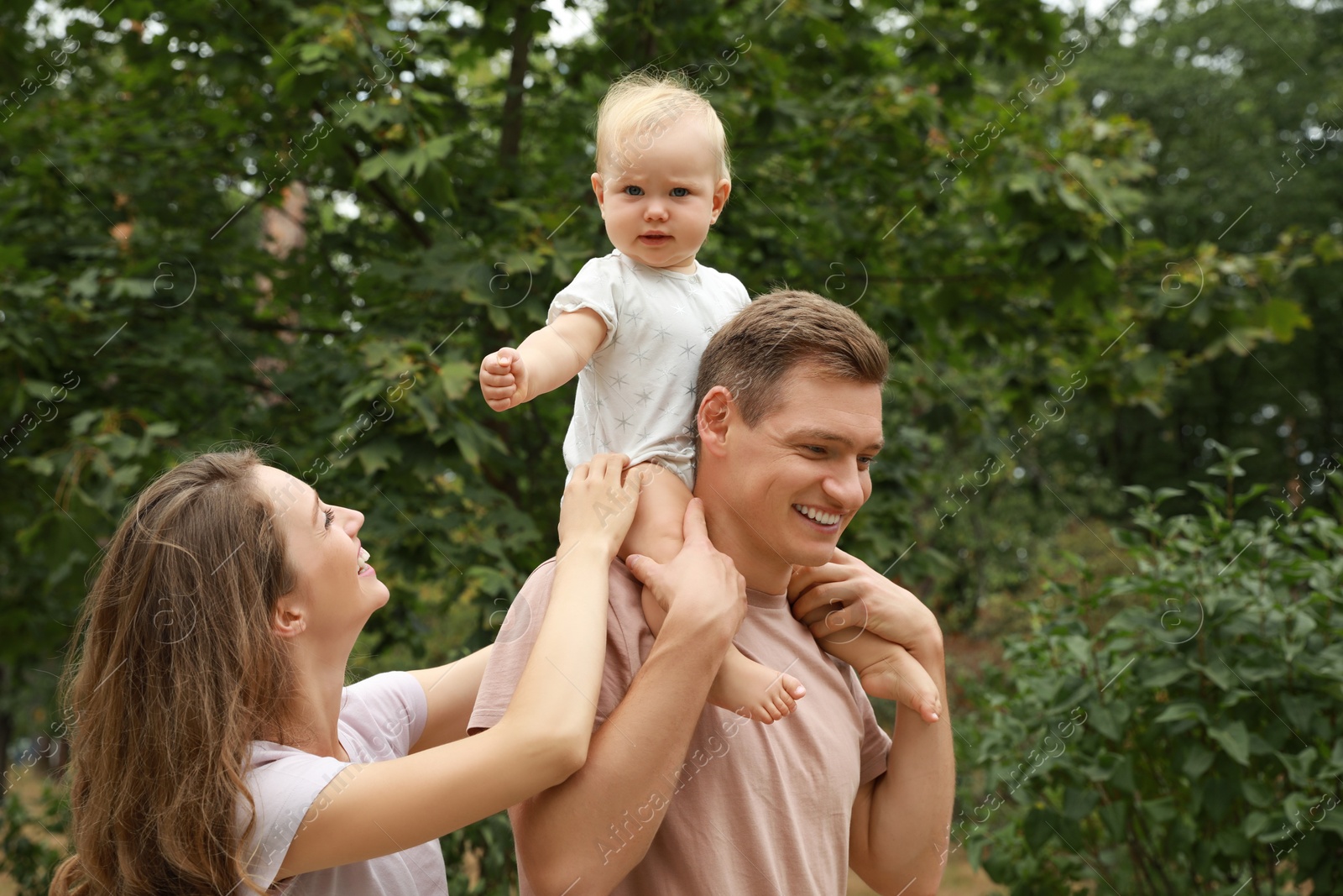 Photo of Parents with their cute baby spending time together outdoors. Happy family