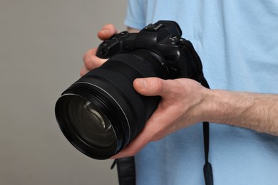 Photographer holding camera on grey background, closeup