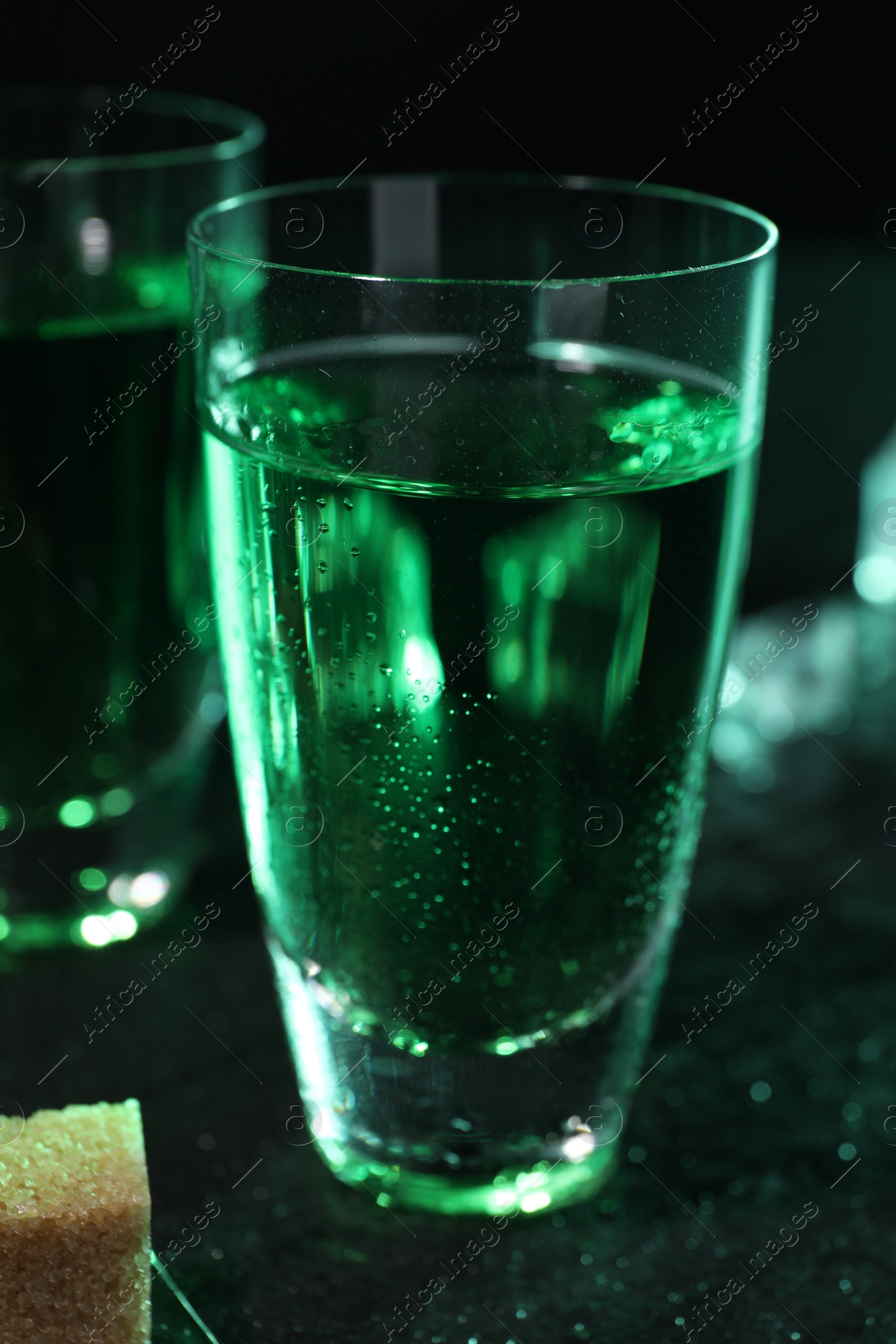 Photo of Absinthe in shot glass on gray table, closeup. Alcoholic drink