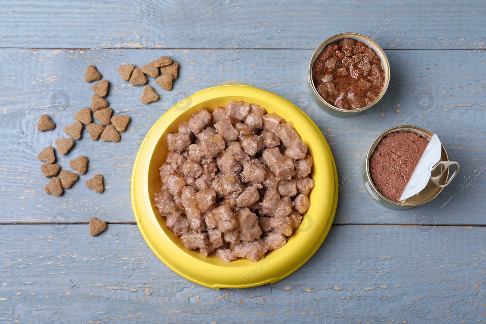 Photo of Wet and dry pet food on blue wooden table, flat lay
