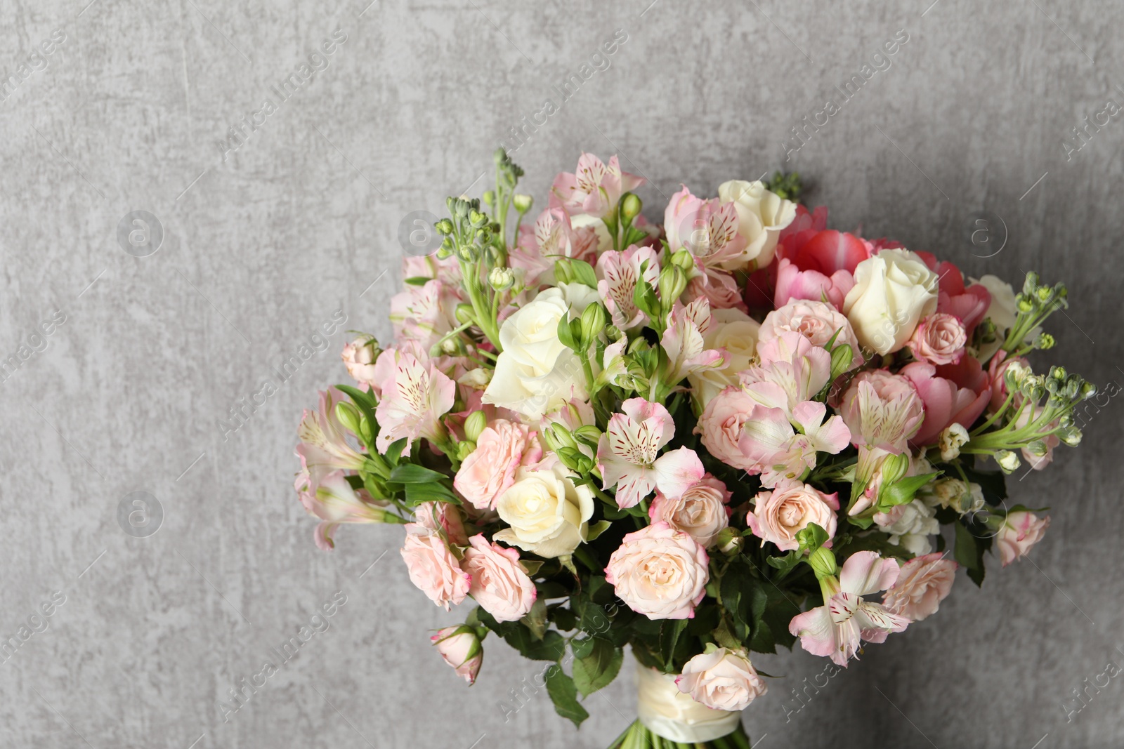 Photo of Beautiful bouquet of fresh flowers near grey wall