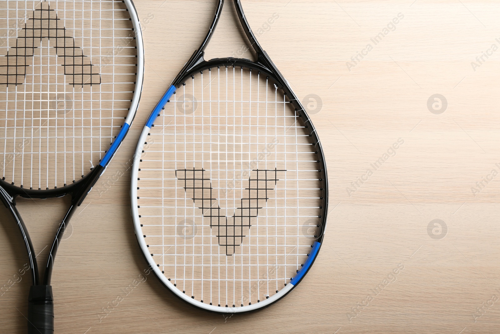 Photo of Tennis rackets on wooden table, flat lay. Sports equipment