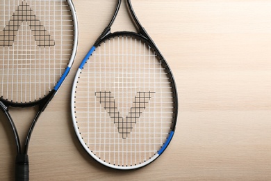 Photo of Tennis rackets on wooden table, flat lay. Sports equipment